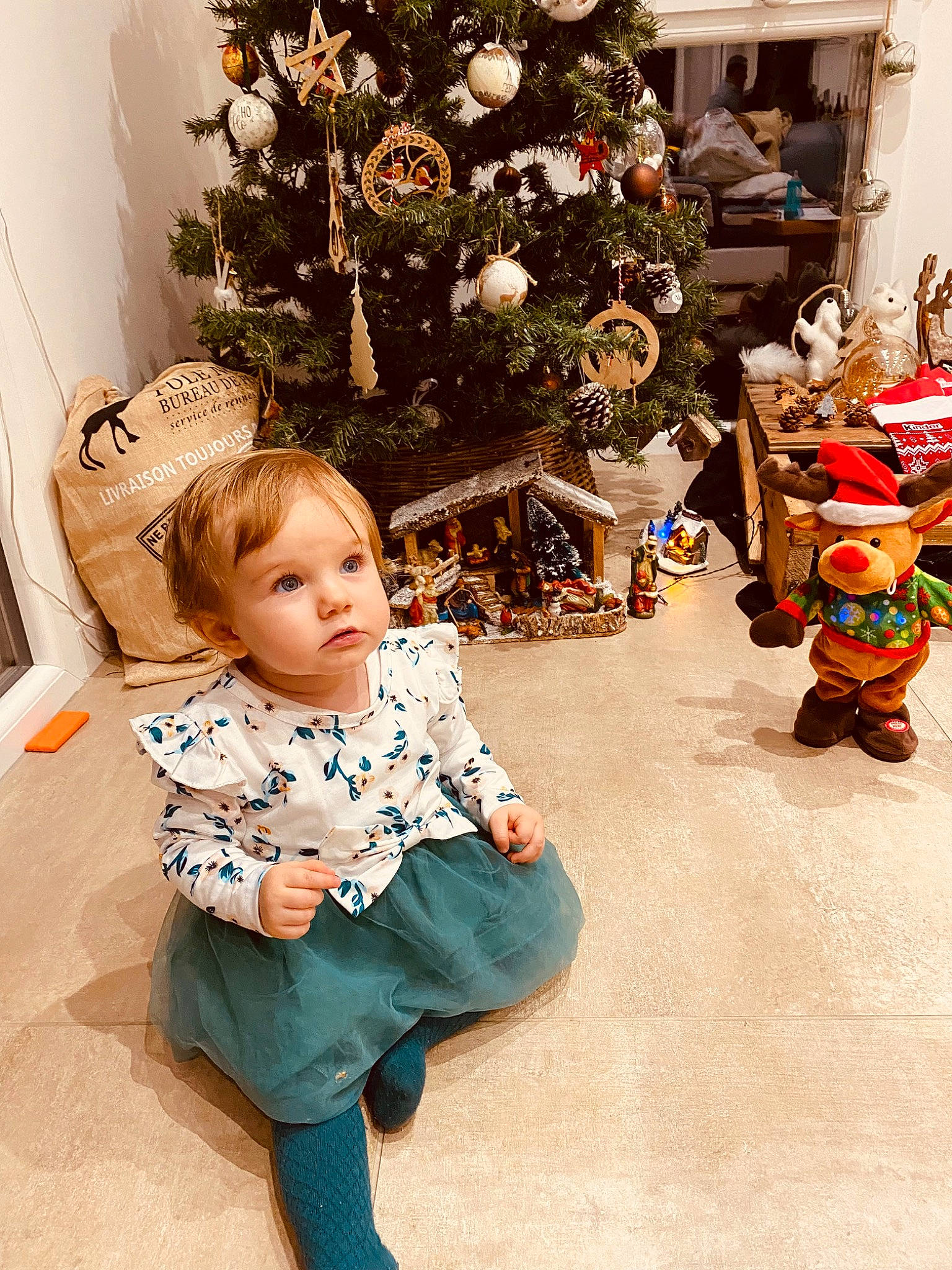 Mia a rejoint le concours — aidez-le/la à gagner de superbes lots ! baby_toddler_clothing, christmas, christmas_decoration, christmas_eve, christmas_ornament, christmas_tree, conifer, event, fun, happy, holiday, holiday_ornament, human_body, ornament, person, plant, sleeve, standing, toddler, tree