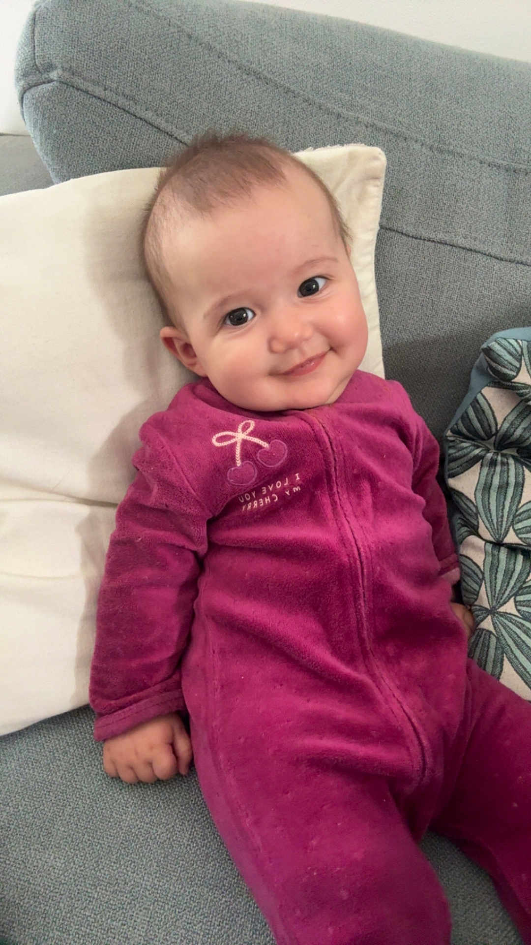 Thaïs participe au concours pour gagner de l'argent avec cette photo : baby, child, smiling, onesie, purple_clothing, couch, pillow, indoor, cute, face, person, infant, seated, happy, soft_fabric, hand, head, eyes, home, cozy