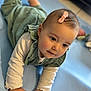 baby, blue_mat, child, close_up, curious, cute, expression, face, green_outfit, hands, human, indoors, infant, laying_down, pink_bow, portrait, skin, soft_lighting, toddler, young_child