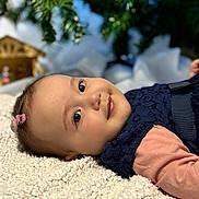 Thaïs participe au concours pour gagner de l'argent avec cette photo : baby, blanket, child, closeup, clothing, cute, decorations, face, greenery, hair_clip, holiday, indoors, infant, lying_down, navy_dress, peach_sleeves, portrait, smile, soft_texture, young_child