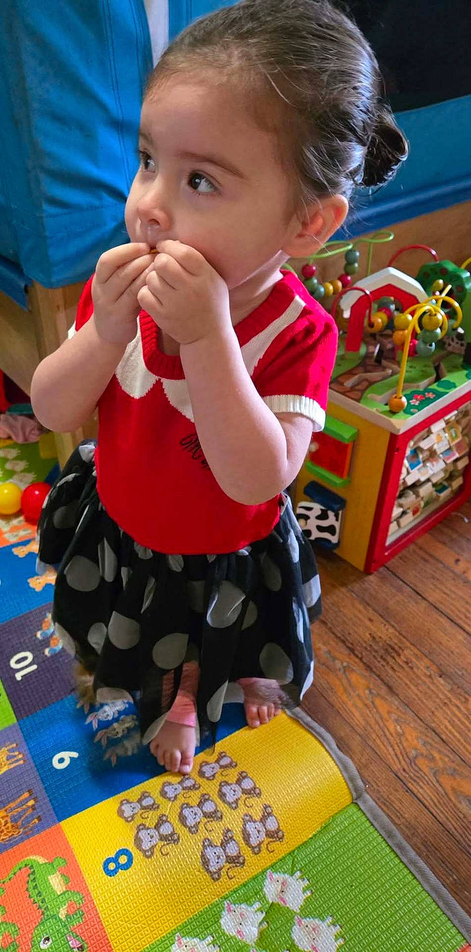 baby, biting, bodypart, clothing, couch, cutlery, dress, eating, face, finger, food, furniture, hand, head, indoors, person, photography, portrait, sitting, spoon