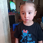 Kiera is registered to the contest to win money with this photo: black_tshirt, braided_hair, child, clothing, curious, drawer, expression, face, floor, furniture, hair, indoor, living_room, person, portrait, standing, television, toddler, toy, young_child