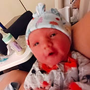Aaliyahrose joined the competition — help win amazing prizes! baby, infant, hat, clothing, bottle, hand, face, person, indoors, newborn, cute, patterned_hat, colorful_outfit, blur, closeup, soft_focus, human, bedroom, care, rest