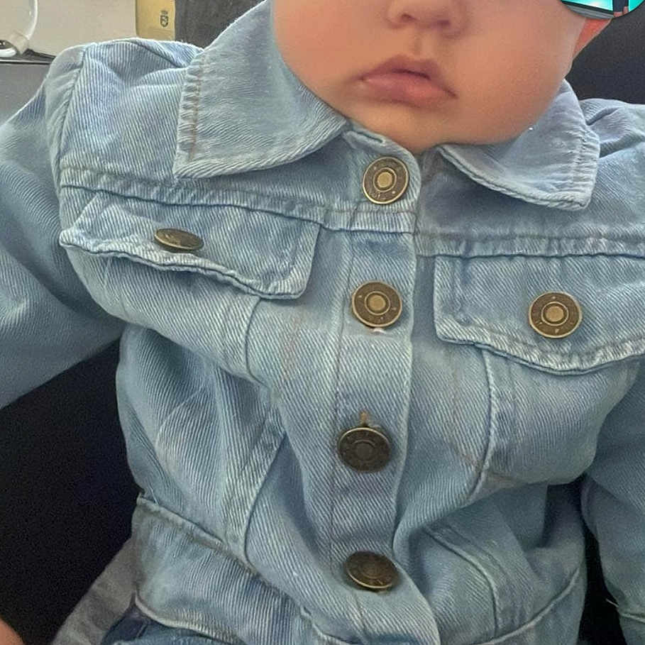 Maëlann participe au concours pour gagner de l'argent avec cette photo : baby, blue_eyes, button, casual, child, clothing, curious, cute, denim_jacket, expression, face, furniture, home, indoor, jeans, person, portrait, sitting, window, young_child