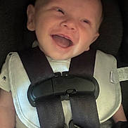 Theodore is registered to the contest to win money with this photo: baby, car_seat, child, smile, harness, safety, happy, infant, seat_belt, white_clothing, black_straps, child_safety, cute, portrait, young, person, baby_smiling, seat, closeup, child_protection