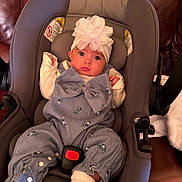 Josephine joined the competition — help win amazing prizes! baby, car_seat, headband, flower, clothing, infant, seat_belt, couch, leather, indoor, cute, child, face, person, portrait, sitting, white_socks, curious, comfort, small