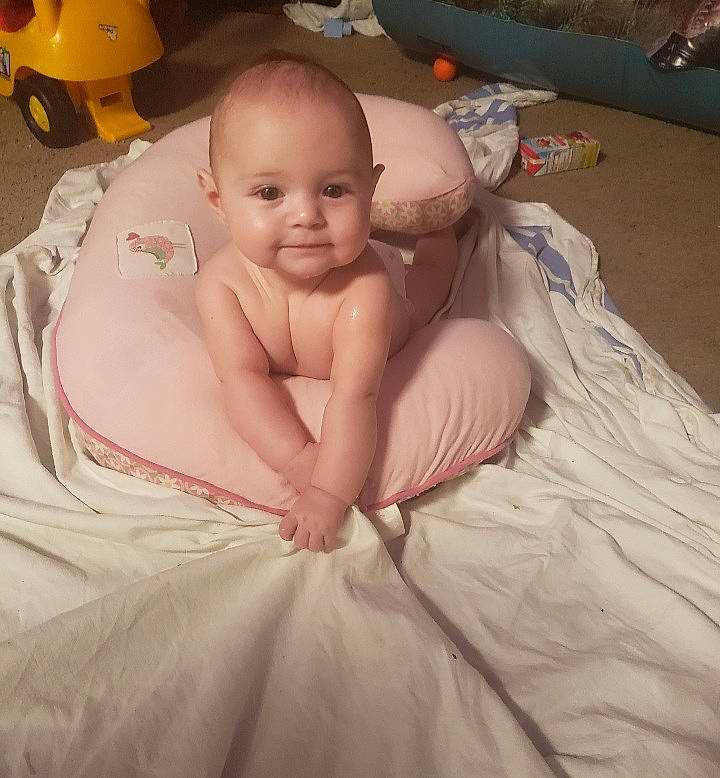 Mckenzie is registered to the contest to win money with this photo: abdomen, baby, bed, bedding, cheek, chest, child, comfort, fun, head, human_body, joy, linens, person, pink, sitting, skin, smile, stomach, toddler