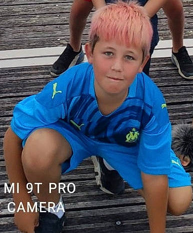 Nolan participe au concours pour gagner de l'argent avec cette photo : blue, child, cool, electric_blue, eye, finger, grass, happy, human_leg, joint, knee, leisure, person, shorts, sitting, sleeve, soil, sportswear, t_shirt, thigh