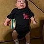 arm, baby, child, clothing, couch, cute, expression, face, furniture, head, indoor, infant, leg, onesie, person, plush, relaxing, skin, socks, tambourine