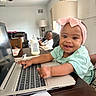 baby, child, infant, smiling, happy, portrait, pink_bow, headband, mint_shirt, laptop, computer, keyboard, bottle, indoor, living_room, table, chair, adult, home, technology