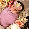 newborn, baby, infant, child, portrait, sleeping, bundled, pink_blanket, floral_headband, flowers, bouquet, cozy, basket, text_overlay, watermark, close_up, indoors, soft_lighting, adorable, photography