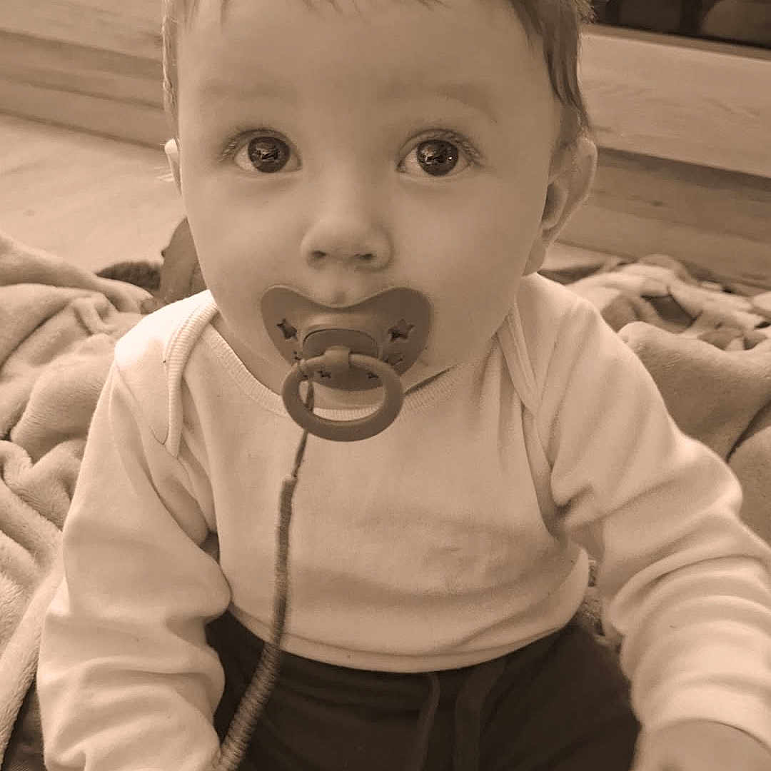 Clark a rejoint le concours — aidez-le/la à gagner de superbes lots ! baby, blanket, candid, child, closeup, clothing, curious, cute, expression, face, floor, hands, indoor, infant, pacifier, person, play, sepia, toy, young