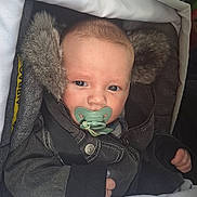 Clark participe au concours pour gagner de l'argent avec cette photo : baby, pacifier, blanket, jacket, fur, child, infant, warm_clothing, car_seat, seatbelt, closeup, face, cute, indoors, portrait, expression, bundle, comfort, hood, sleepy