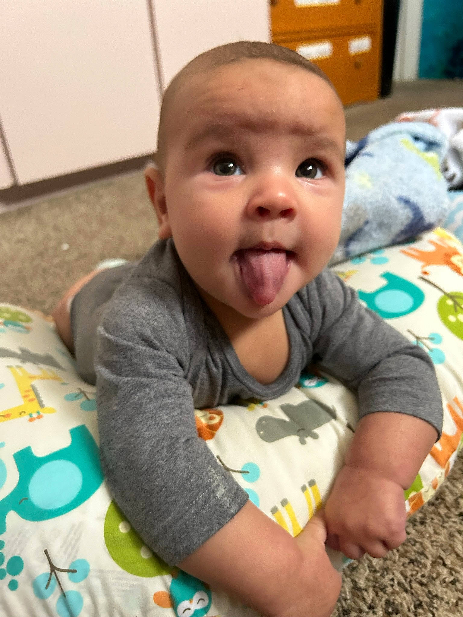 Malachi is registered to the contest to win money with this photo: baby, baby_toddler_clothing, cheek, child, chin, comfort, eye, facial_expression, flooring, fun, grass, happy, iris, mouth, nose, person, skin, sleeve, smile, surprise