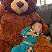Thiago Garcias is registered to the contest to win money with this photo: baby, teddy_bear, plush, couch, child, indoor, clothing, blue_outfit, socks, cute, soft_toy, relaxing, portrait, furniture, smiling, toy, home, infant, cozy, resting