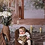 baby, basket, brown_fur_chair, candles, child, cozy, decor, dried_oranges, floor_tiles, gold_dress, headband, indoor, infant, pine_cone, portrait, smile, snow_effect, studio_shot, white_roses, winter