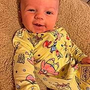 Devon Jr is registered to the contest to win money with this photo: baby, infant, smiling, yellow_clothing, onesie, spongebob, blanket, soft_texture, happy, cute, face, portrait, child, indoor, cozy, hand, young_child, playful, comfort, casual