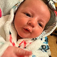 Devon Jr is registered to the contest to win money with this photo: baby, infant, face, hand, hooded_blanket, cozy, indoor, curious_expression, soft_texture, close_up, person, newborn, cute, warm_clothing, skin, portrait, child, young, warmth, comfort