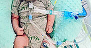 Bryant is registered to the contest to win money with this photo: baby, infant, hospital, medical_equipment, oxygen_tube, onesie, shoes, pillow, bed, monitor, tubes, cute, child, patient, healthcare, newborn, person, lying_down, baby_clothes, medical_care
