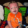 Bryant joined the competition — help win amazing prizes! child, infant, orange_shirt, blanket, medical_equipment, breathing_tube, face, indoor, seated, expression, curious, human, skin, head, diaper, redness, colorful_blanket, healthcare, person, closeup