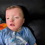 Bryant is registered to the contest to win money with this photo: child, boy, medical_equipment, breathing_tube, tshirt, captain_america, blue_shirt, indoor, leather_sofa, person, face, healthcare, medical_care, resting, young_child, casual_clothing, closeup, sitting, patient, home