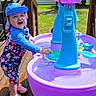 Isabella joined the competition — help win amazing prizes! toddler, child, water_table, outdoor, sun_hat, floral_clothing, smiling, playing, deck, wooden_deck, summer, sunny, toy, water_play, pink_shoes, tree, grass, house, happy, daytime