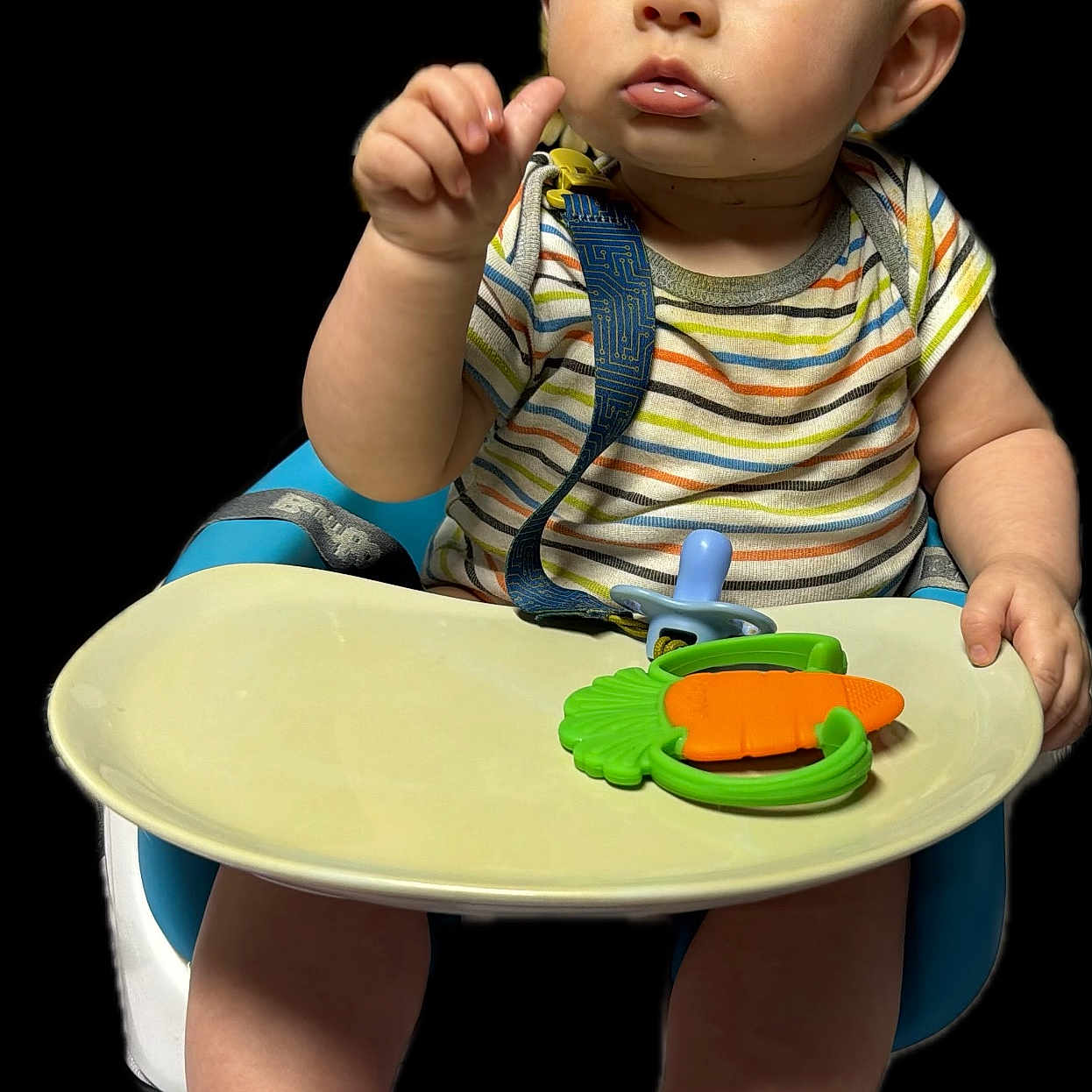 Evren is registered to the contest to win money with this photo: baby, child, high_chair, teether, carrot_toy, striped_shirt, blue_eyes, bare_feet, infant, cute, portrait, expression, sitting, hand, fingers, skin, face, indoor, isolated, background