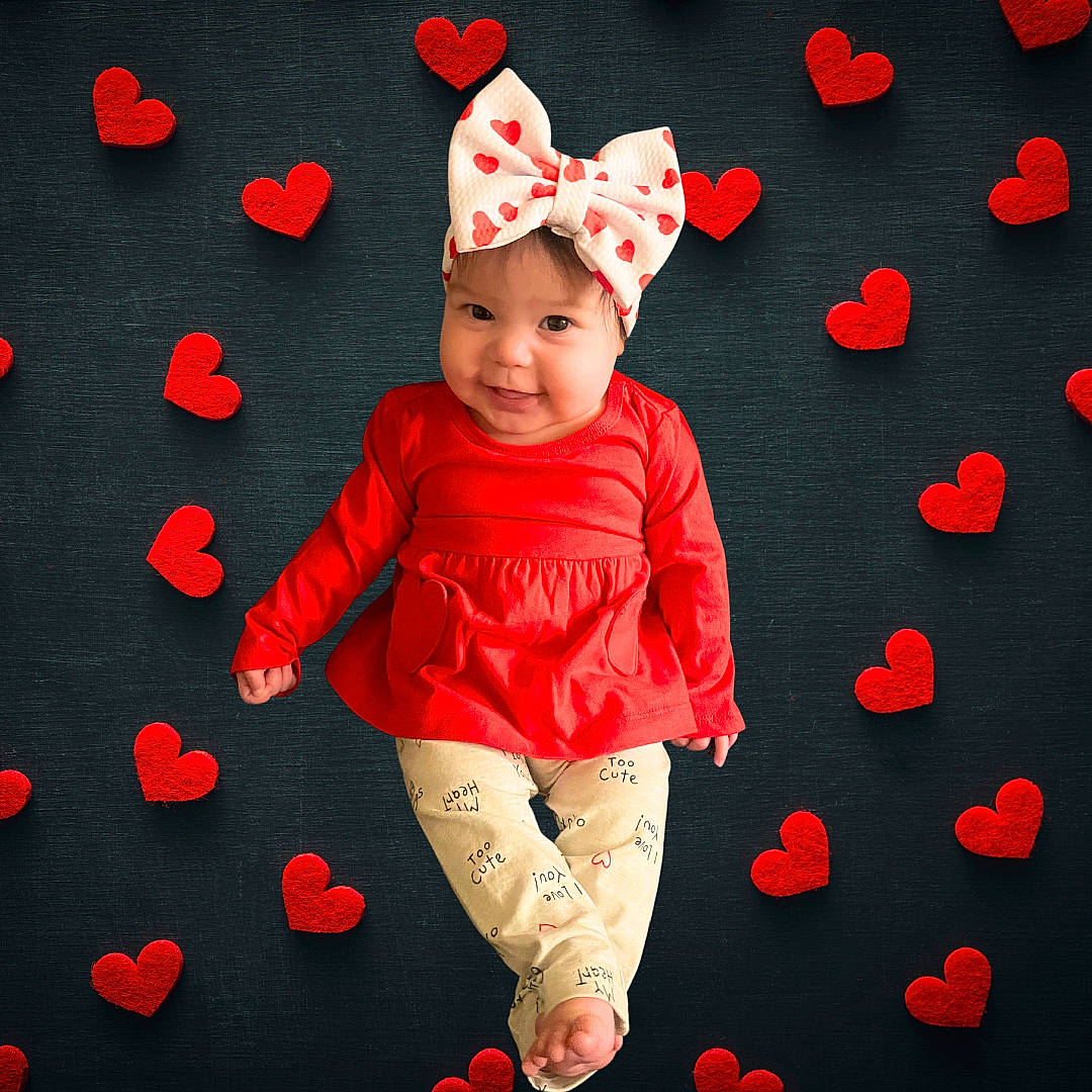 Caroline is registered to the contest to win money with this photo: baby, baby_toddler_clothing, cap, child, costume_hat, event, flooring, fun, happy, headwear, holiday, human_body, magenta, outerwear, pattern, person, pink, red, sleeve, smile