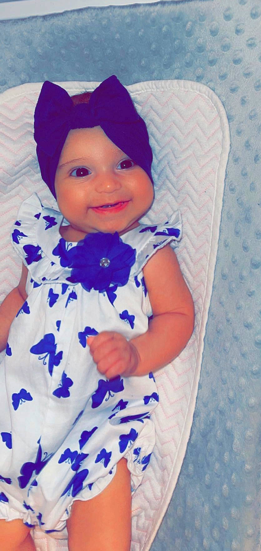 Julia is registered to the contest to win money with this photo: arm, baby, baby_toddler_clothing, cap, child, clothing, dress, face, finger, happy, hat, headgear, headwear, joy, person, pink, purple, skin, sleeve, smile