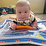 Wylde is registered to the contest to win money with this photo: baby, bib, carpet, child, clothing, cute, expression, face, floor, hands, indoor, infant, light, orange_toy, person, play_mat, toy, tummy_time, window, young