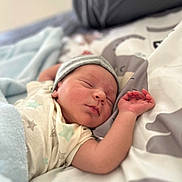 Amar is registered to the contest to win money with this photo: baby, newborn, sleeping, infant, hat, bed, blanket, soft, cozy, peaceful, rest, cute, child, pajamas, star_pattern, hand, face, closeup, indoors, comfort