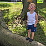 child, boy, smiling, tree, outdoor, grass, nature, casual_clothing, tank_top, shorts, footwear, nike, sunlight, daytime, happy, playful, young_child, standing, greenery, park