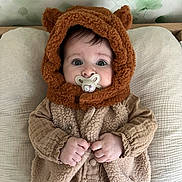 Victoire a rejoint le concours — aidez-le/la à gagner de superbes lots ! baby, pacifier, hood, teddy_bear, vest, fleece, infant, clothing, hands, face, eyes, cushion, blanket, indoor, portrait, cute, soft_texture, wallpaper, sleeping_area, babywearing