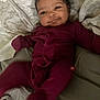 baby, babysuit, bed, blanket, child, cozy, cute, expression, face, happy, indoors, infant, lying_down, maroon_outfit, one_person, pillow, skin, smiling, soft, young