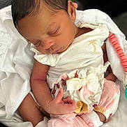 Marjae is registered to the contest to win money with this photo: baby, blanket, bow, clothing, cozy, cute, face, floral_pattern, hand, indoors, infant, newborn, peaceful, person, pink, resting, sleeping, small, soft, white