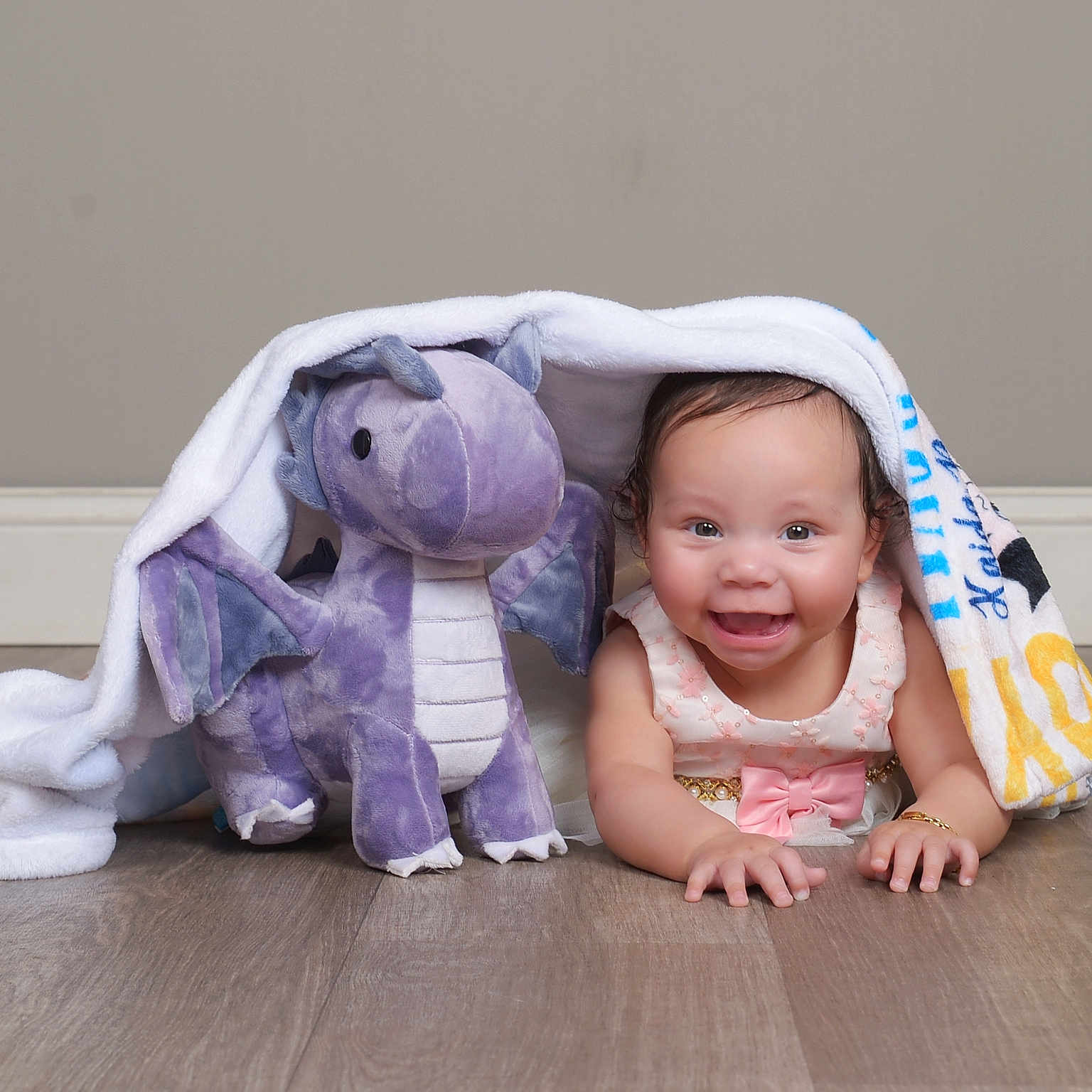 Kaida Little Dragon joined the competition — help win amazing prizes! baby, background, blanket, bracelet, child, crawling, cute, face, floor, happy, indoors, person, pink_bow, playtime, plush_toy, purple_dragon, smiling, toy, wall, wooden_floor