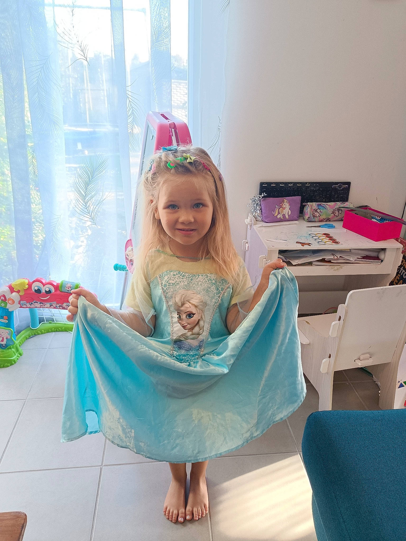 Manuela a rejoint le concours — aidez-le/la à gagner de superbes lots ! barefoot, child, dress, event, fashion_accessory, fashion_design, foot, fun, happy, headpiece, joy, leisure, magenta, person, pink, room, sandal, shipping_box, sitting, smile