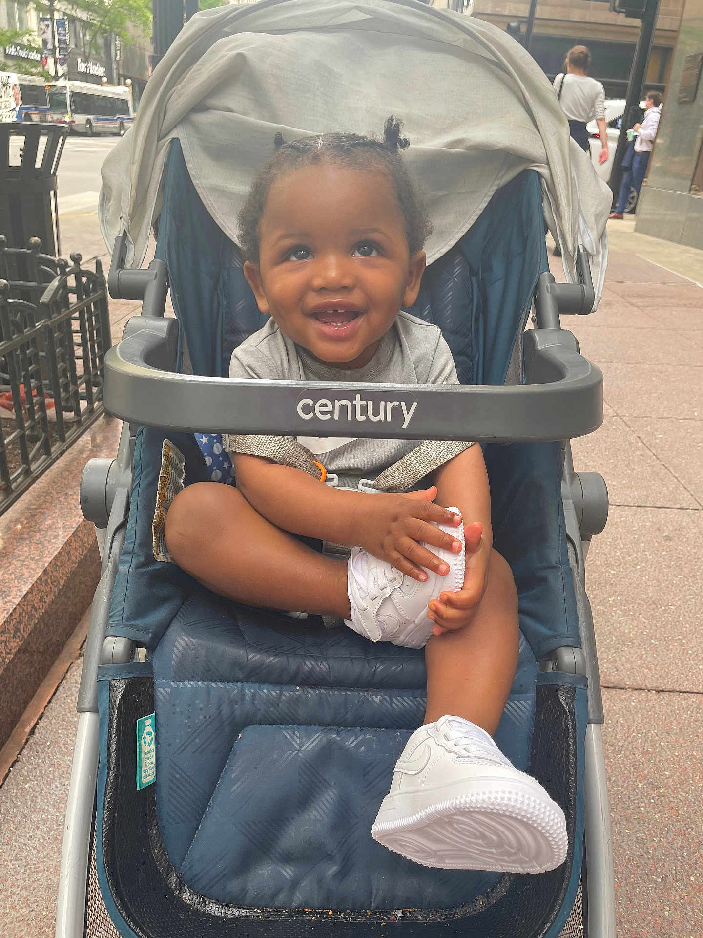 Bryson joined the competition — help win amazing prizes! child, toddler, stroller, shoe, white_shoe, smiling, happy, outdoor, sidewalk, urban, person, baby, clothing, seat, hand, face, hair, cute, city, daylight