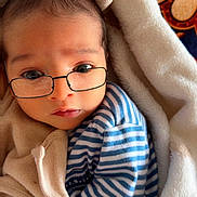 Mhiirr is registered to the contest to win money with this photo: baby, infant, glasses, blanket, striped_clothing, soft_texture, cute, portrait, closeup, sleepy_eyes, cozy, hand, face, newborn, indoors, warm, child, young, resting, wrapped