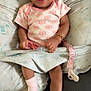 baby, smiling, infant, cushion, pink_clothing, socks, bracelet, pacifier, indoor, cute, happy, child, seat, fabric, patterned, relaxed, young, skin, portrait, comfort