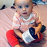 Joshua joined the competition — help win amazing prizes! baby, child, mohawk, blue_eyes, striped_shirt, red_pants, bed, bedroom, container, curious, sitting, barefoot, indoors, person, cute, young_child, expression, holding, casual, portrait