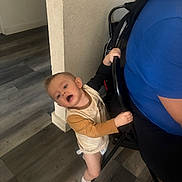 Joshua joined the competition — help win amazing prizes! toddler, child, indoor, floor, wooden_floor, chair, person, blue_shirt, wall, curious, holding, standing, casual, expression, home, young_child, socks, light, hair, diaper
