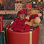 Nyemiah joined the competition — help win amazing prizes! baby, red_outfit, bow, teddy_bear, gift_boxes, christmas_tree, holiday_decor, smiling, indoor, festive, plush_toy, floor, basket, cozy, child, cute, seasonal, warm_lighting, portrait, celebration
