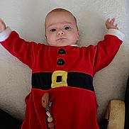 Ilona a rejoint le concours — aidez-le/la à gagner de superbes lots ! arms_up, baby, beads, child, closeup, clothing, cute, expression, face, head, indoors, infant, lying_down, pacifier_clip, person, portrait, red_clothing, shoe, soft_surface, white_background