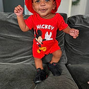 Nasir Cayden joined the competition — help win amazing prizes! black_shoes, casual, child, couch, cute, fashion, gray_couch, happy, home_interior, indoor, mickey_mouse, person, playful, portrait, red_clothing, red_hat, smiling, standing, toddler, young_child