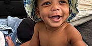 Nasir Cayden joined the competition — help win amazing prizes! accessory, baby, bedroom, blanket, bucket_hat, child, clothing, cute, diaper, face, foot, furniture, hand, happy, hat, indoor, person, skin, smile, toy