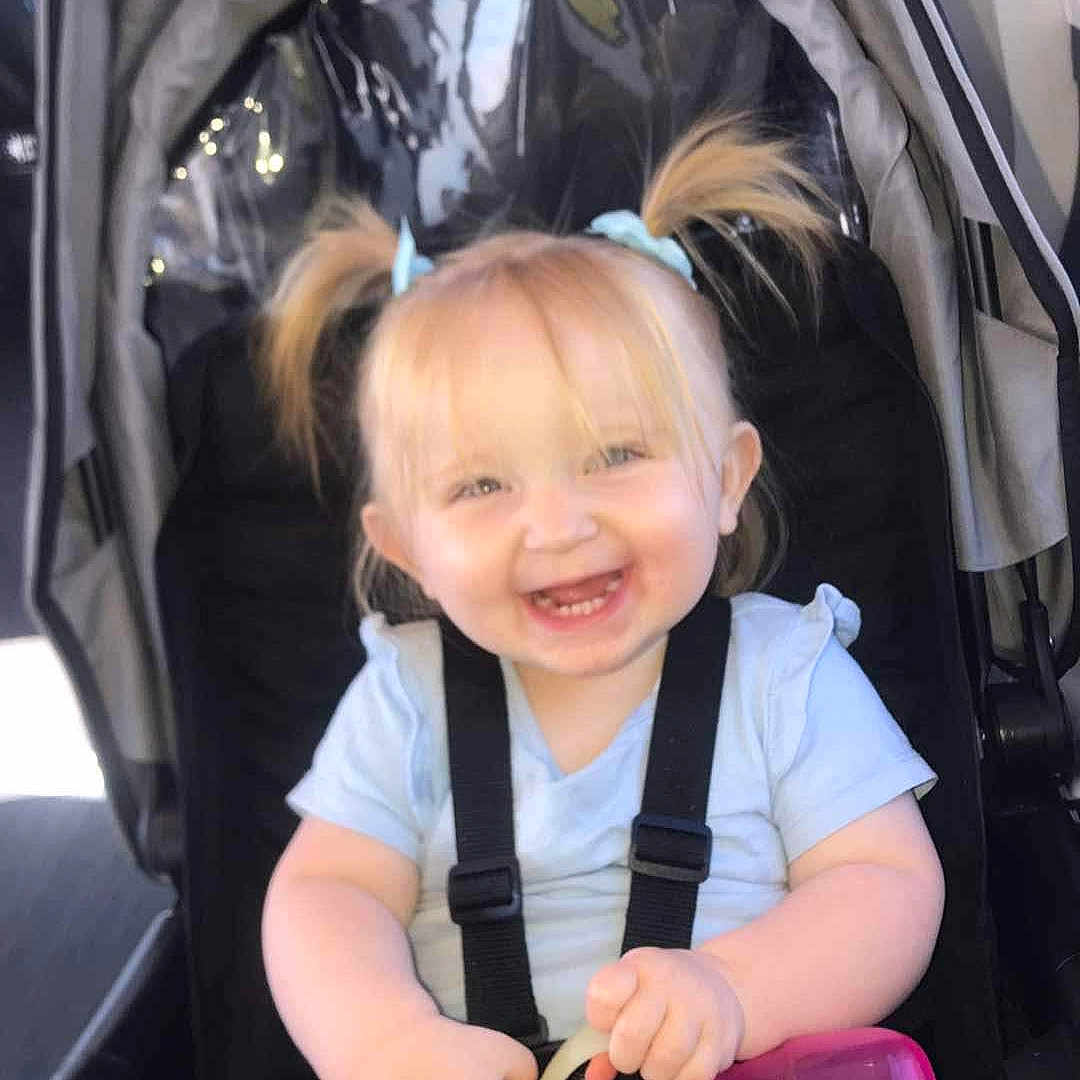 Delilah joined the competition — help win amazing prizes! accessories, baby, bag, clothing, coat, cutlery, electronics, face, happy, head, jacket, person, phone, photography, portrait, smile, spoon, stroller, transportation, vehicle