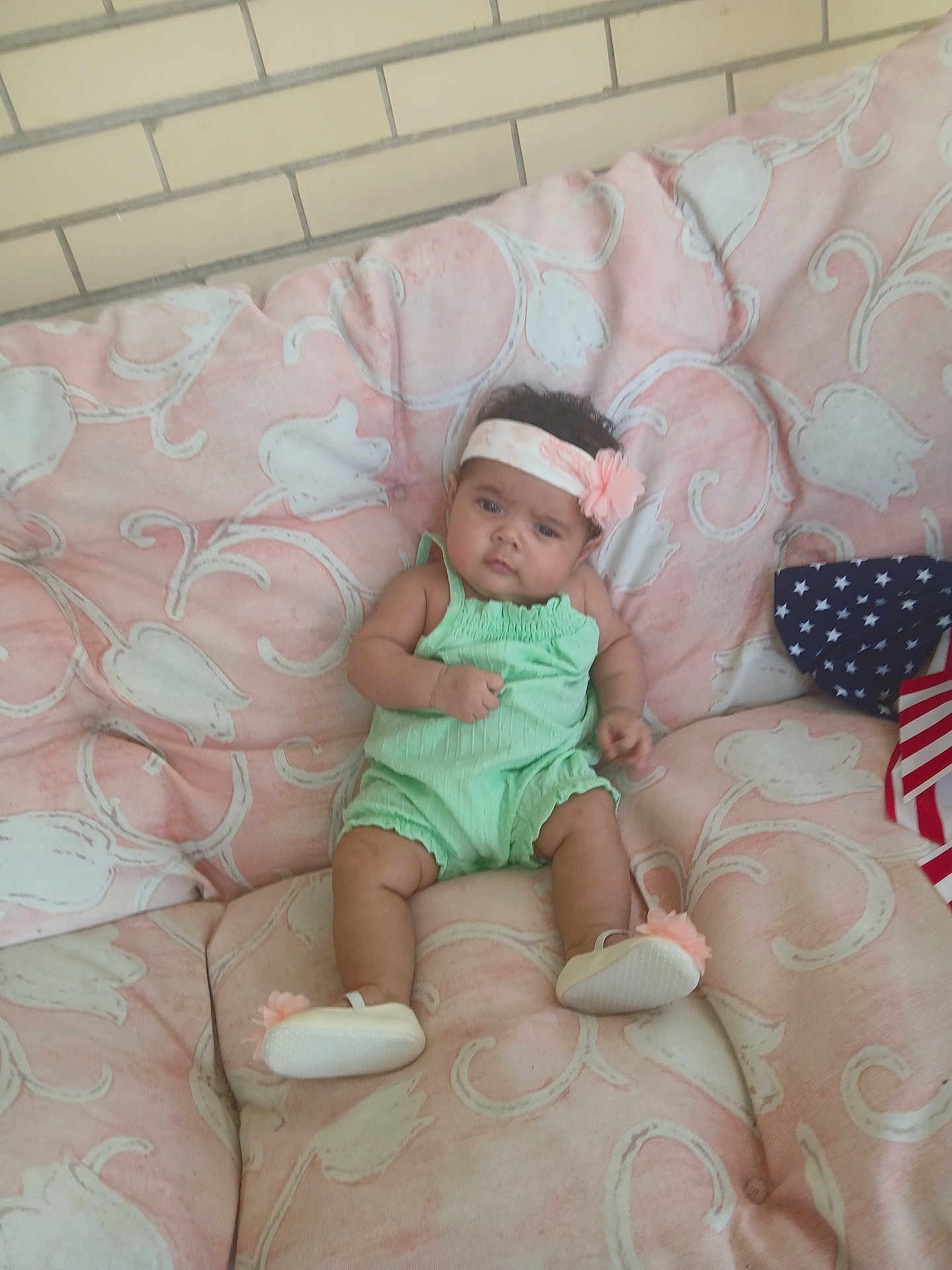 Mila joined the competition — help win amazing prizes! baby, child, comfortable, curious, cushion, cute, face, flower, green, headband, indoors, infant, pattern, person, pink, plush, romper, seated, shoes, young