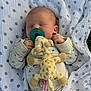 baby, newborn, pacifier, plush_toy, giraffe, blanket, sleeping, infant, polka_dot, clothing, cute, resting, soft, cozy, outdoor, grass, toddler, peaceful, child, portrait