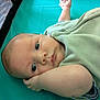 Knoxtin is registered to the contest to win money with this photo: baby, infant, face, blue_eyes, blanket, lying_down, arm, hand, soft_fabric, playpen, crib, curious, close_up, skin, head, expression, young_child, indoors, teal_background, portrait